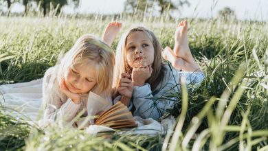 little girls lying on green grass field